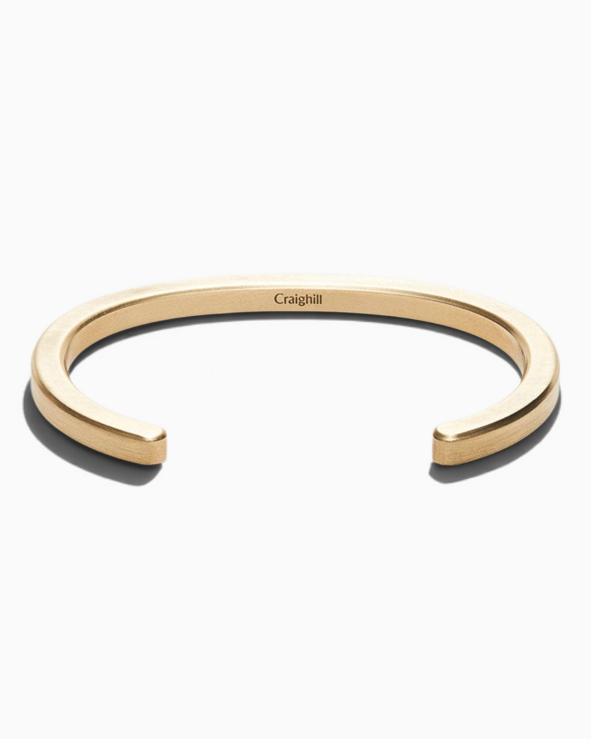 Vitruta Radial Cuff pirinç bileklik, oval profilli ve ışığı yansıtan eğimli kenar detaylı minimalist tasarım.