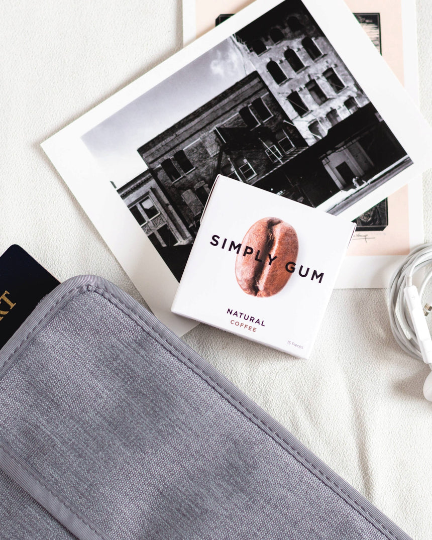 vitruta Simply Gum kahve aromalı bitkisel sakız paketi, yanında pasaport kılıfı ve siyah beyaz şehir fotoğrafı ile