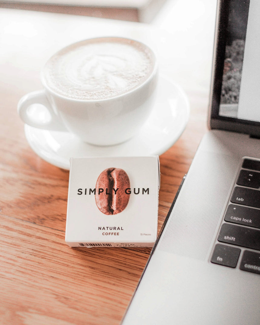 vitruta Simply Gum kahve aromalı bitkisel sakız paketi, yanında bir fincan kahve ve dizüstü bilgisayar ile masada.