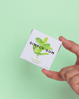 vitruta Simply Gum nane aromalı bitkisel sakız paketi, el tutuşu ile pastel yeşil arka plan üzerinde